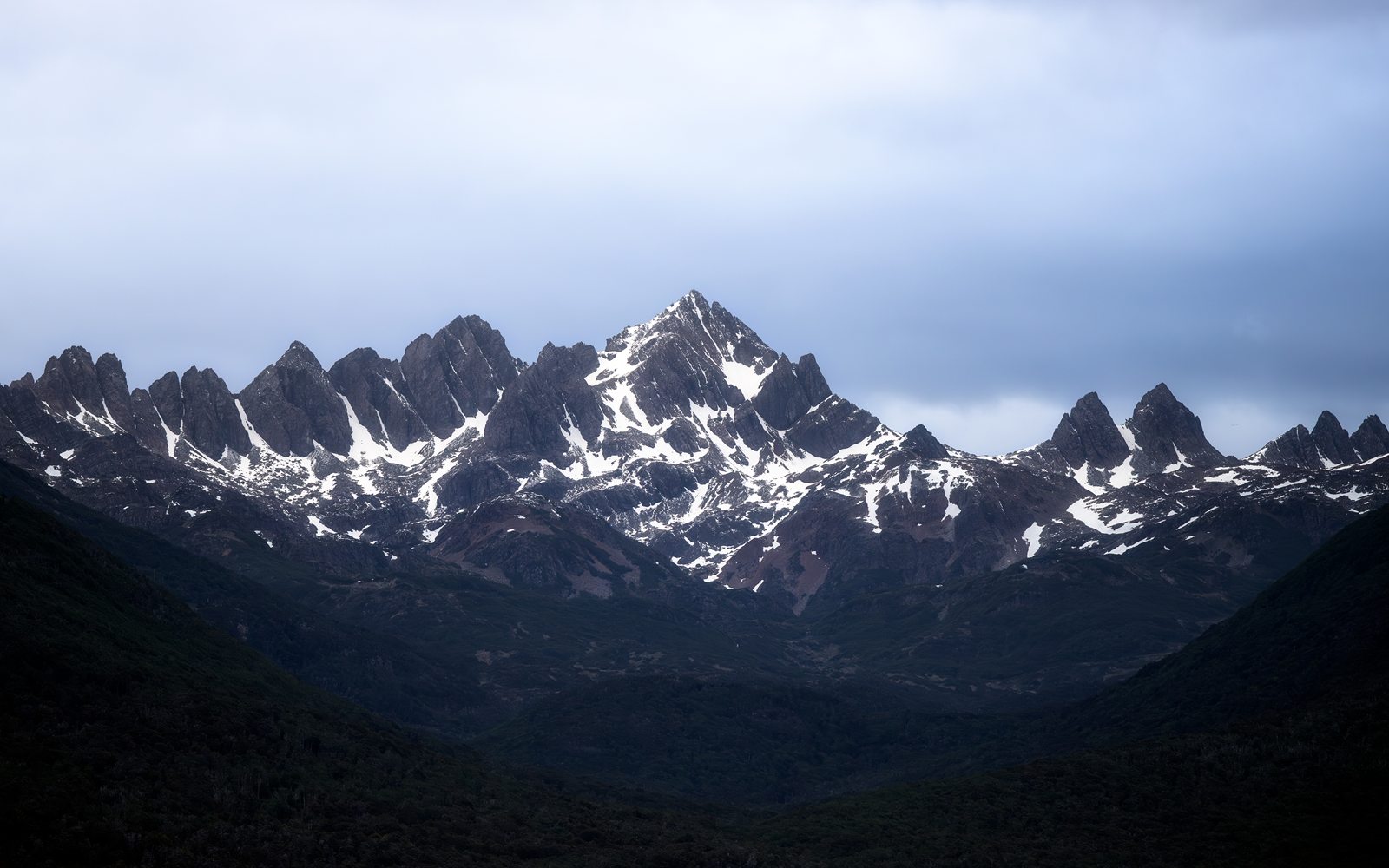 Jagged snow-streaked peaks under a grey sky